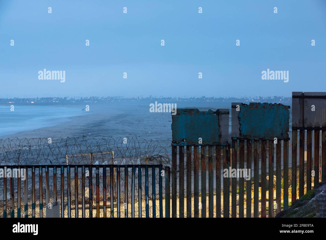 Ein nächtlicher Himmel bildet den Hintergrund für die Grenzmauer der USA und Mexikos in Tijuana, Mexiko. Stockfoto