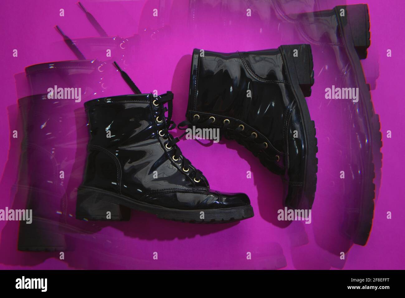 Schwarze glänzende Stiefel in rosa Hintergrund Stockfoto