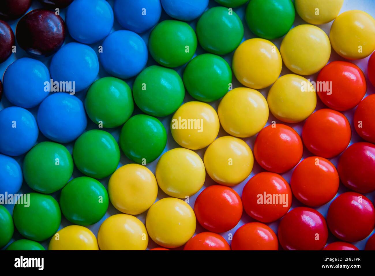 Süße Bonbons in hellen Farben, die flach liegen. Regenbogen Süßigkeiten Hintergrund Stockfoto