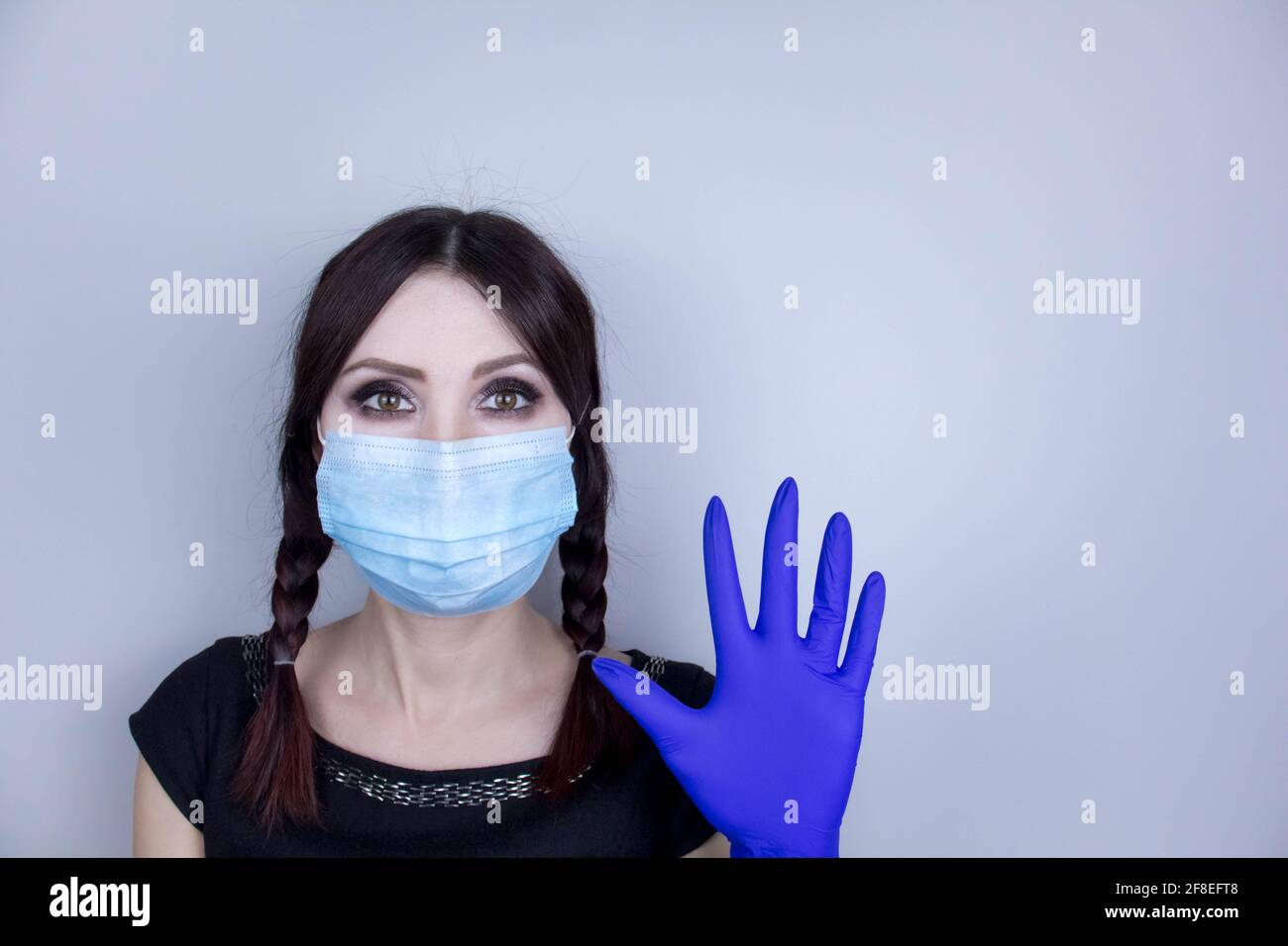 Frau trägt Schutz Gesichtsmaske gegen Coronavirus. Frau in einer Maske, die schockiert oder besorgt mit der Hand nach oben aussieht. Medizinische Maske, medizinische Handschuhe, Close U Stockfoto