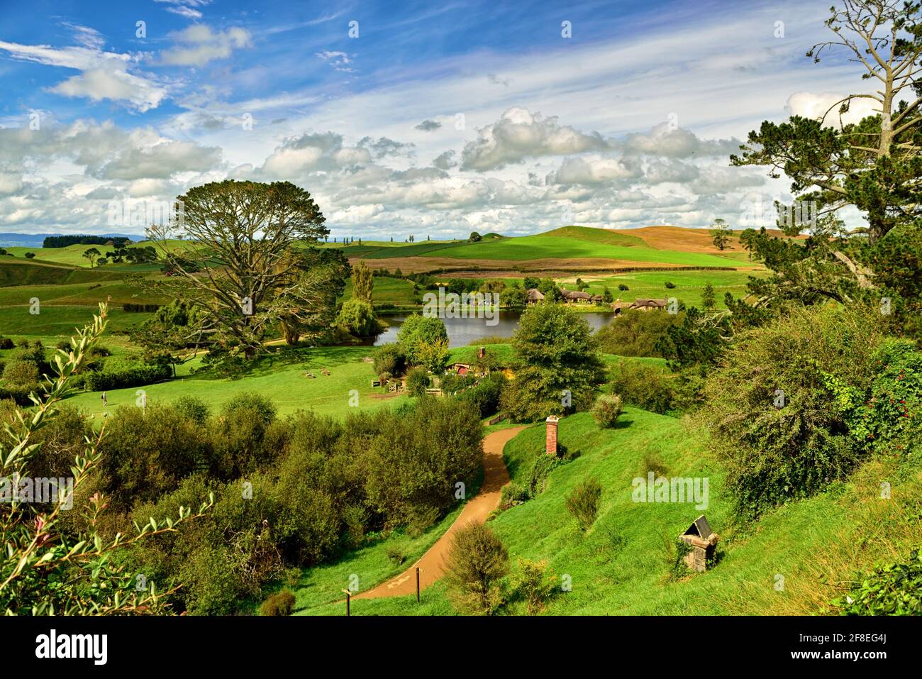 Im Herzen der Landschaft von Hamilton & Waikato, ruhig versteckt hinter grünen Hügeln, ist ein Ort wie kein anderer – Hobbiton Movie Set; The per Stockfoto
