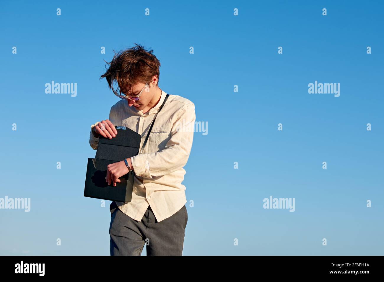 Kaukasischer Mann aus Spanien steht und öffnet seine schwarze Handtasche Auf klarem Himmel Hintergrund Stockfoto