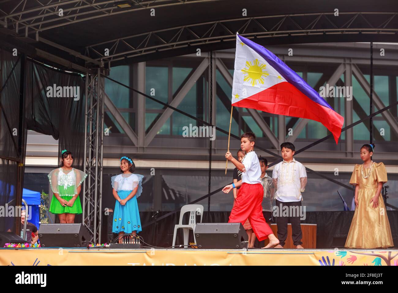 Philippinische Kinder in Nationaltracht tragen die Flagge der Philippinen bei einem multikulturellen Fest. Tauranga, Neuseeland Stockfoto