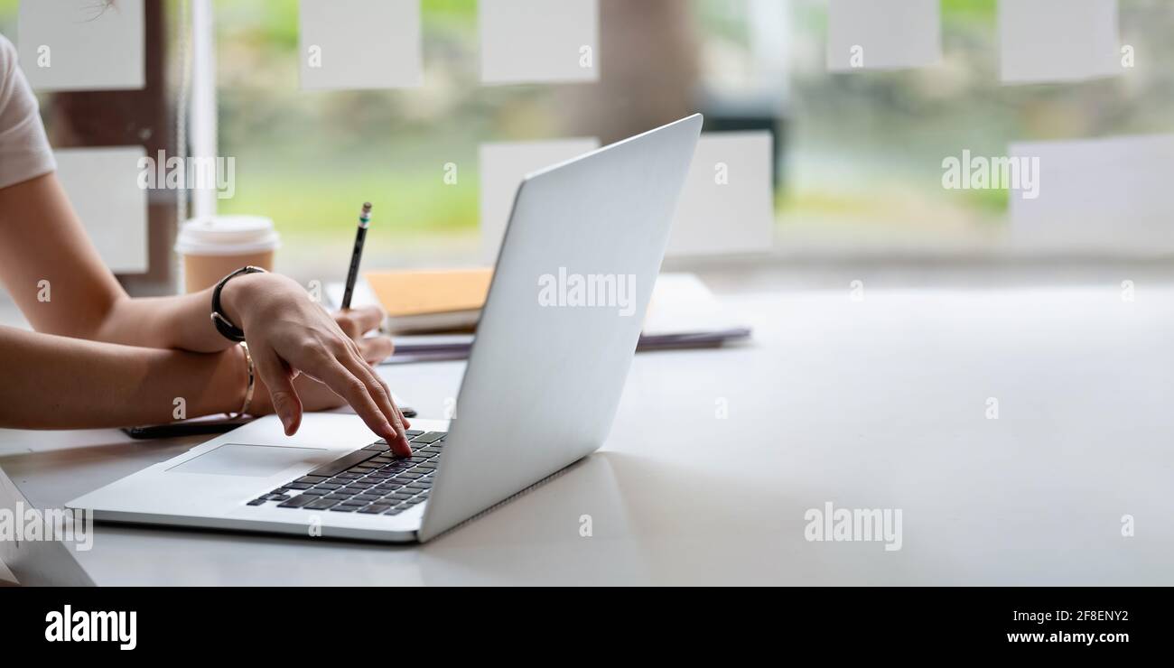 Ausgeschnittenes Foto Hand der Frau schriftlich eine Liste Notizen machen Im Notizblock Online-Arbeiten oder Lernen mit Laptop zu Hause Stockfoto