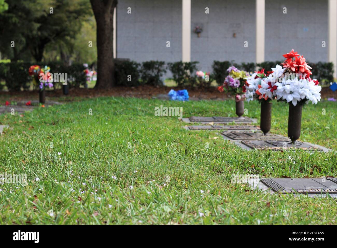 Blumenstrauß, der auf einer Friedhofstafel eines geliebten Verlorenen liegt. Friedhof, Verlust eines geliebten Konzepts. Stockfoto