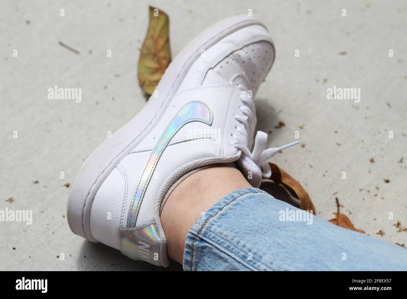 Frau trägt weißen Court Visions Nike Iridescence Air Force One Sneaker mit niedrigem Schnitt. Stockfoto