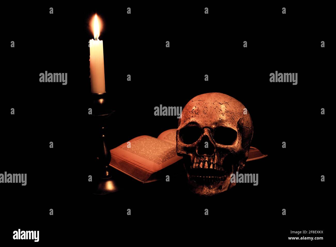 Ein Totenkopf, ein Buch und eine Kerze Stockfoto