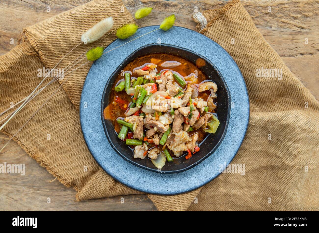 Gebratenes Schweinefleisch mit gerösteter roter Chilischote auf Keramikplatte umrühren. Draufsicht, selektiver Fokus. Stockfoto