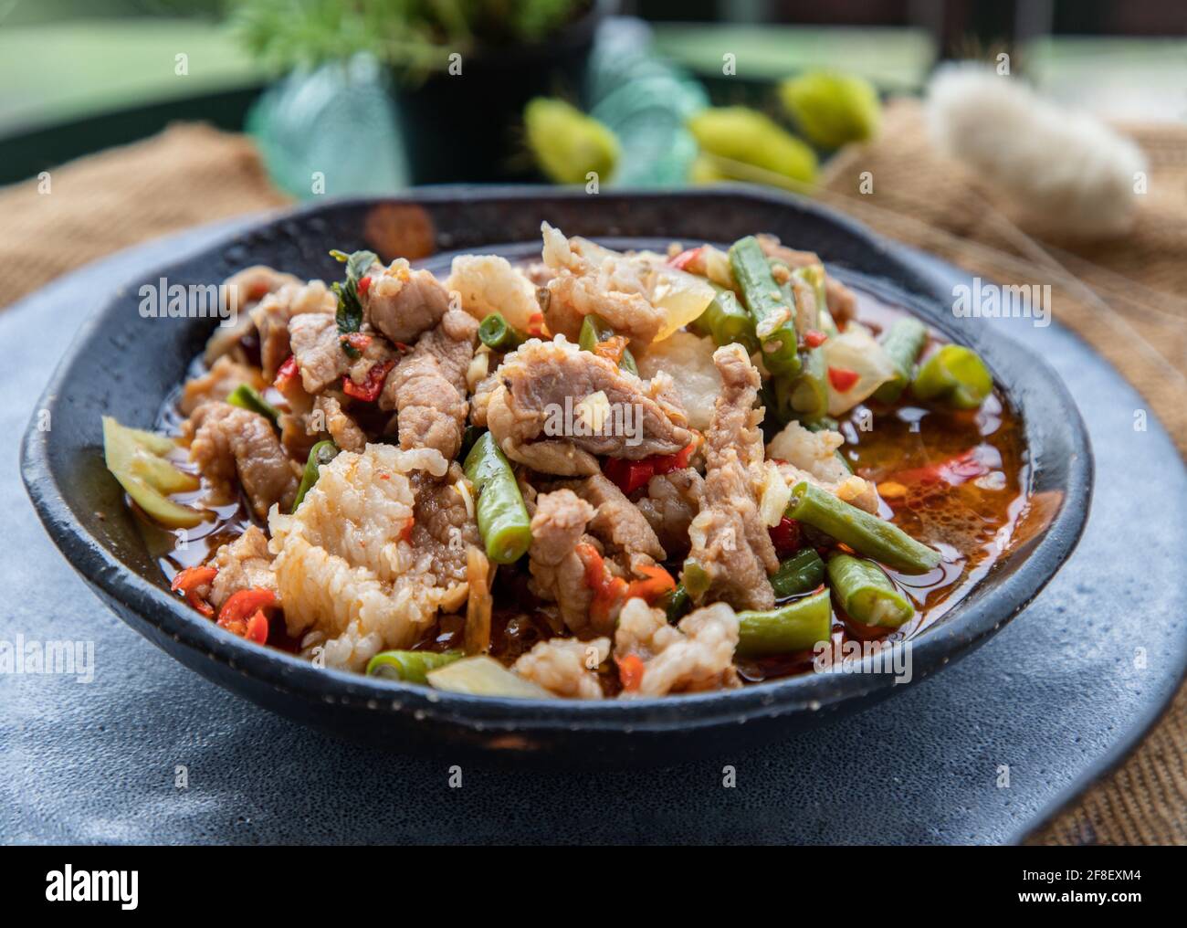Gebratenes Schweinefleisch mit gerösteter roter Chilischote auf Keramikplatte umrühren. Selektiver Fokus. Stockfoto