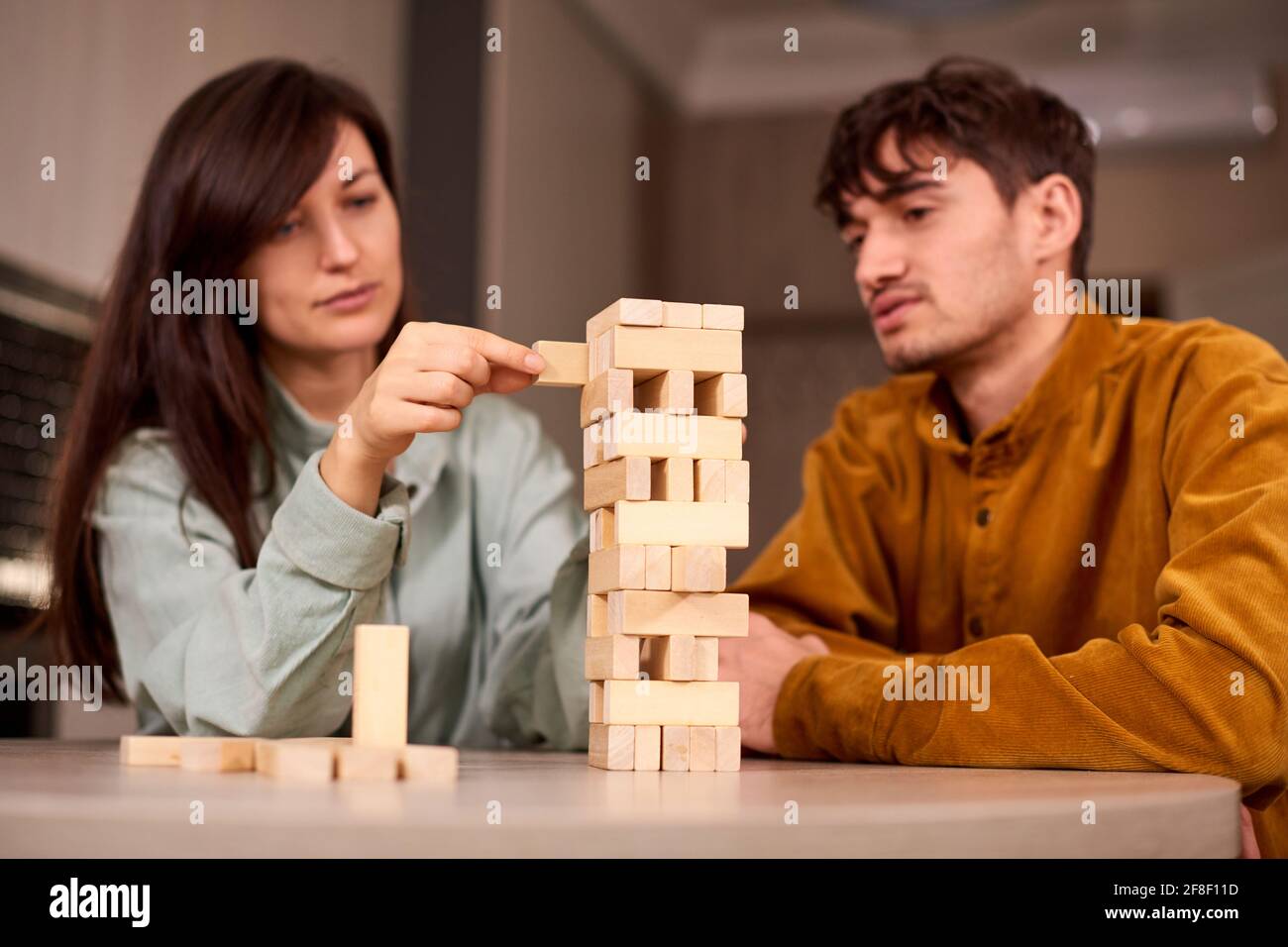 Kerl spielt Jenga mit Freundin zu Hause und verbringt ein Wochenende zusammen Stockfoto