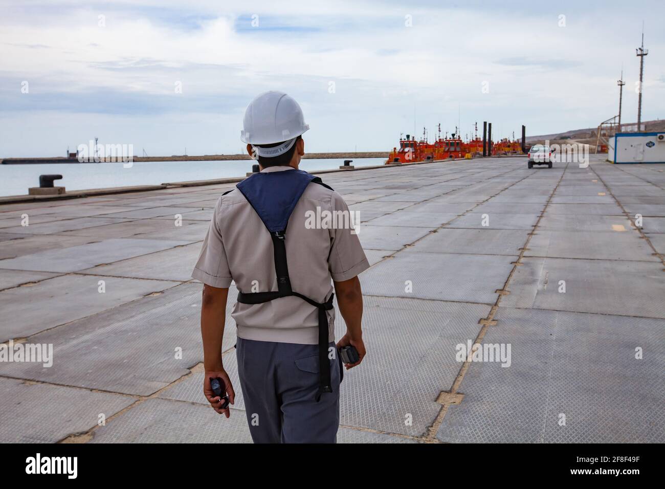 Bucht von Bautino, Mangystau, Kasachstan: Ladeterminal auf dem Kaspischen Meer. Orange Öltankschiffe. Ingenieur in Hardhut und Rettungsweste mit Radio-Set. Stockfoto
