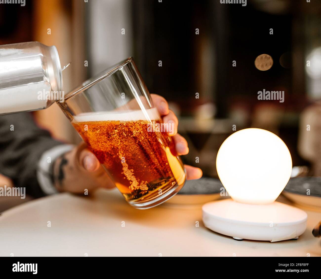 Gießen Sie frisches Bier aus einer Dose ins Glas Stockfoto