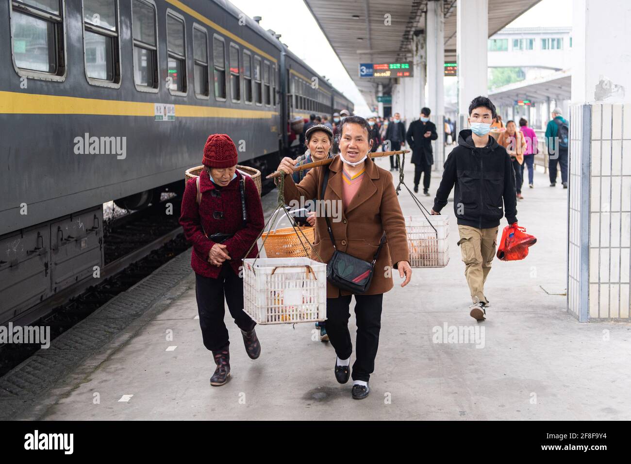 (210414) -- CHANGSHA, 14. April 2021 (Xinhua) -- Passagiere steigen in den Zug 7265 ein, nachdem sie ihre Waren am Bahnhof Jishou in der zentralchinesischen Provinz Hunan verkauft hatten, 11. April 2021. Die 7265/7266/7267-Züge wurden 1995 in Betrieb genommen und erstrecken sich über mehr als 300 Kilometer vom Bahnhof Huaihua zum Bahnhof Lixian. Die Züge fahren in 9 Stunden und 16 Minuten an 37 Haltestellen vorbei. Die Ticketpreise reichen von 1 Yuan bis 23.5 Yuan (etwa 0.15-3.59 US-Dollar), die seit 26 Jahren nicht mehr angehoben wurden. Die Züge fahren durch die Wuling Mountains. Dank ihnen können Dorfbewohner nicht nur Frui tragen Stockfoto