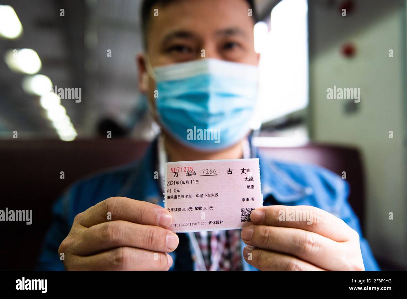 (210414) -- CHANGSHA, 14. April 2021 (Xinhua) -- EIN Passagier legt sein Ticket zum Preis von 1 Yuan im Zug 7266 in der zentralchinesischen Provinz Hunan vor, 11. April 2021. Die 7265/7266/7267-Züge wurden 1995 in Betrieb genommen und erstrecken sich über mehr als 300 Kilometer vom Bahnhof Huaihua zum Bahnhof Lixian. Die Züge fahren in 9 Stunden und 16 Minuten an 37 Haltestellen vorbei. Die Ticketpreise reichen von 1 Yuan bis 23.5 Yuan (etwa 0.15-3.59 US-Dollar), die seit 26 Jahren nicht mehr angehoben wurden. Die Züge fahren durch die Wuling Mountains. Dank ihnen können Dorfbewohner nicht nur Obst, Gemüse und tragen Stockfoto