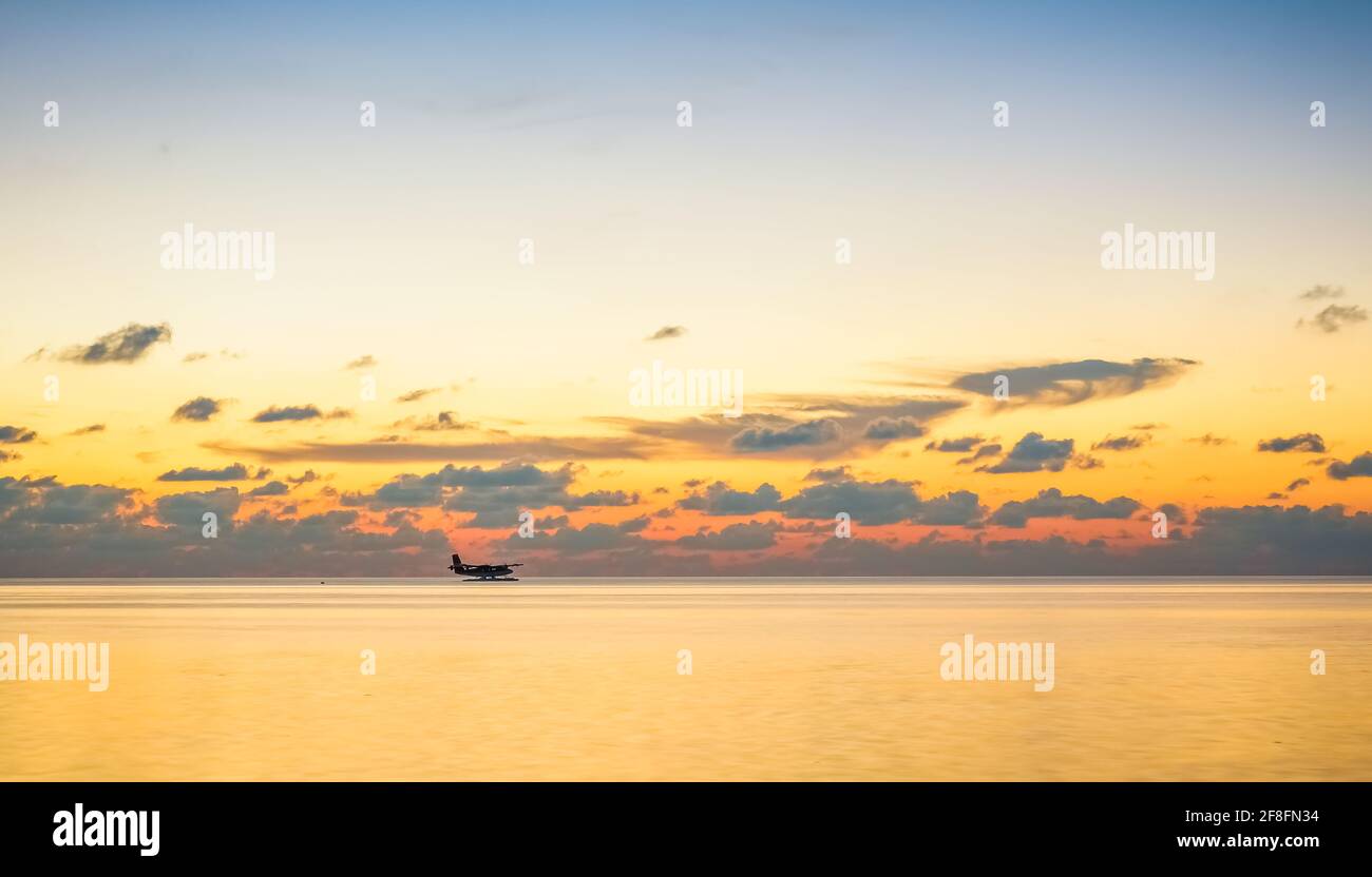 Landung eines Wasserflugzeugs auf der maledivischen Lagune bei Sonnenuntergang. Luxuriöses Reisekonzept Stockfoto