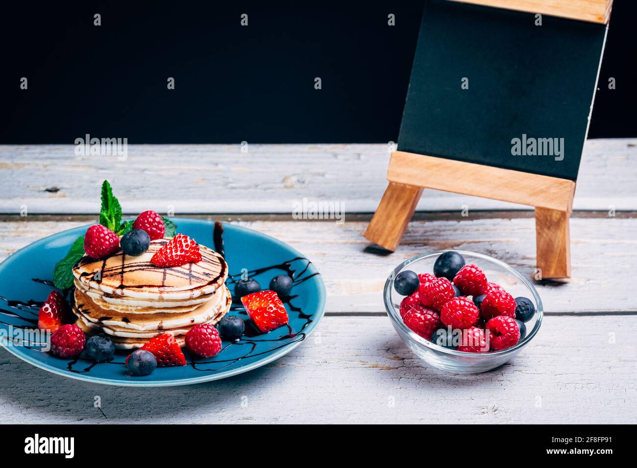 Pfannkuchen mit Schokoladensirup und Stücken von frischem Obst mit Minzblättern und Minze. Heidelbeeren und Himbeeren. Gesunde Ernährung. Copy space Stockfoto