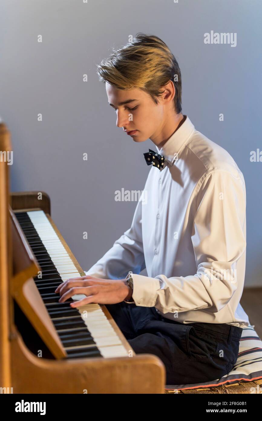 Weißes Hemd Junge mit Fliege spielt Klavier zu Hause Stockfoto