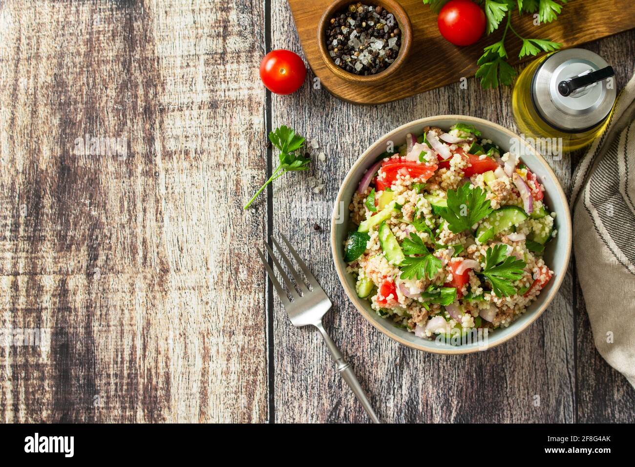 Essen Diät-Konzept, Thunfisch-Salat. Couscous-Salat mit konservierten Thunfisch, Tomaten, Gurken und lila Zwiebeln auf rustikalem Holztisch. Draufsicht flach liegend. Stockfoto