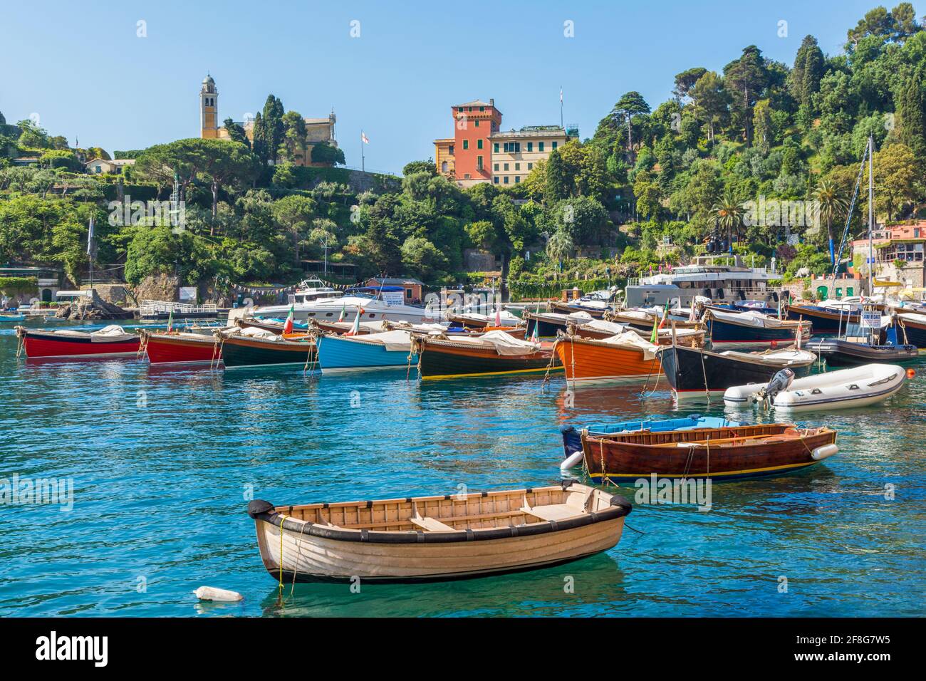 Portofino, Provinz Genua, Ligurien, italienische Riviera, Italien.  Boote im Hafen mit dem Dorf hinter. Stockfoto