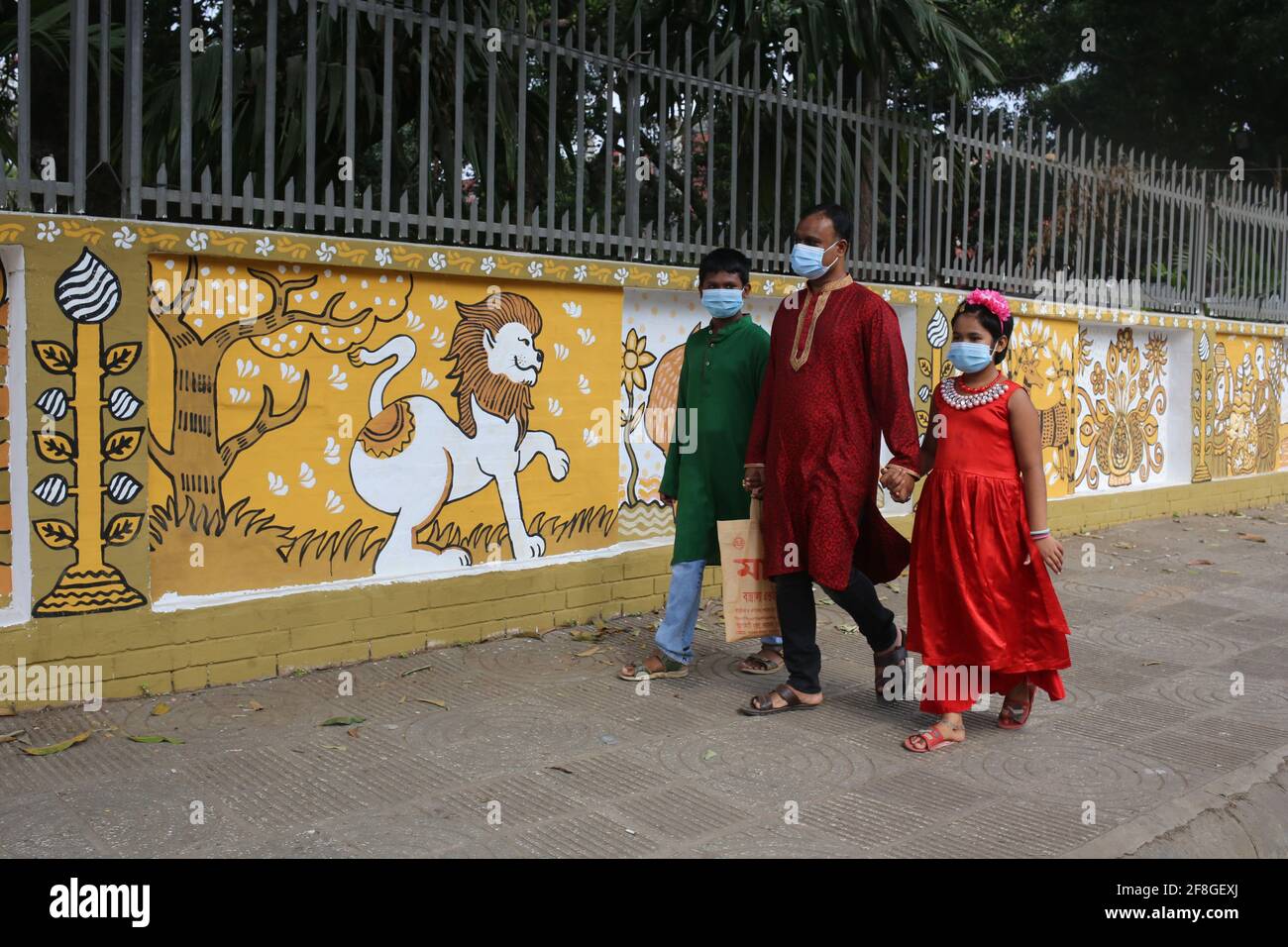 14. April 2021: Pohela Boishakh ist das größte Festival Bengalis. Alle Formalitäten wurden aufgrund der Corona-Epidemie gestrichen. Um Menschenmassen zu vermeiden, wurde eine strikte Sperre auferlegt. Ein Vater mit seinen beiden Kindern geht jedoch vor der Charukla Bhaban, dem Ort, von dem aus normalerweise der Hauptzug des neuen Jahres beginnt, obwohl sie aufgrund der COVID-19-Pandemie keine anderen Formalitäten erledigen konnten, um das neue Jahr zu feiern. Kredit: MD. Rakibul Hasan/ZUMA Wire/Alamy Live Nachrichten Stockfoto