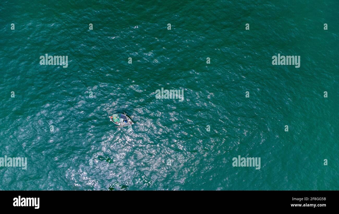 Einsames Boot mit zwei Fischern im grünen Meer Stockfoto