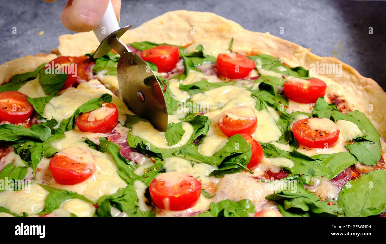 Pizza mit Käse, Tomaten, Spinat und Räucherwurst Stockfoto