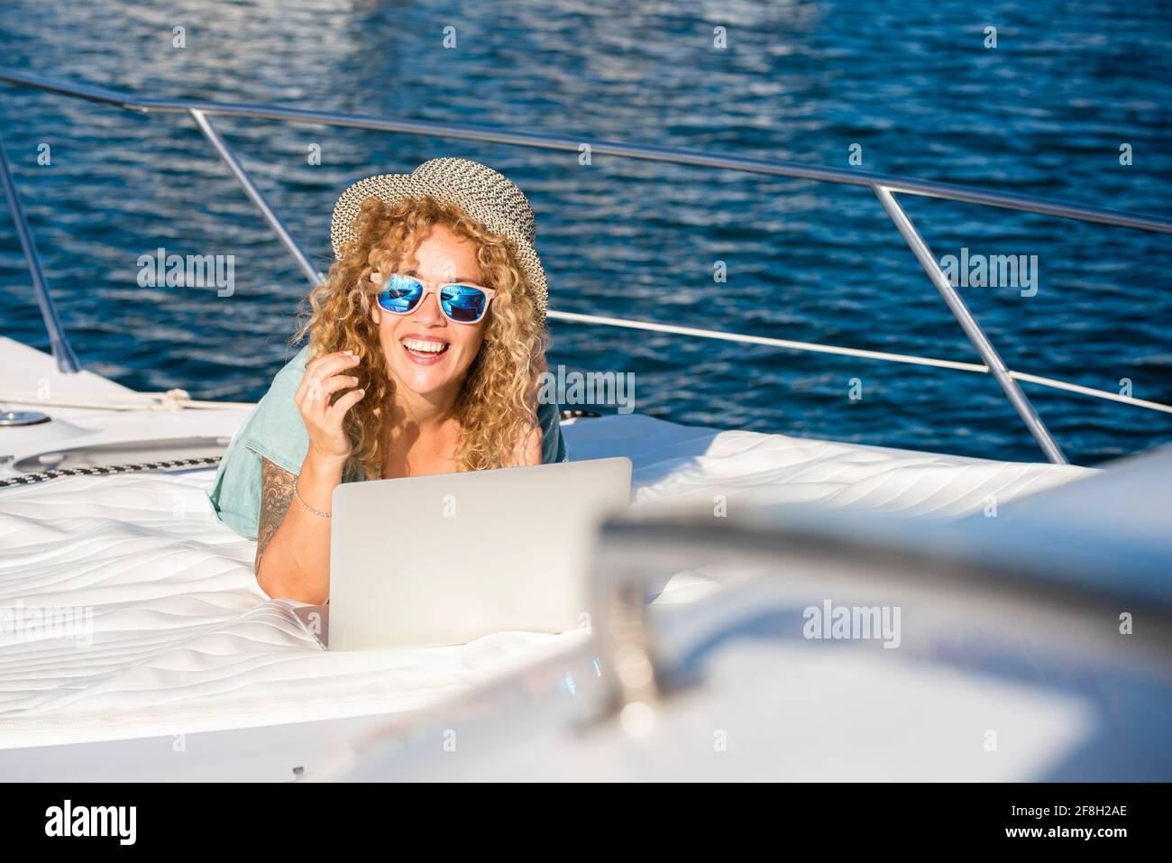 Glückliche Touristen genießen die Sonne im Sommerurlaub Legen auf dem Boot in der Reise Kreuzfahrt Aktivität - weiblich Die Leute lächeln und verwenden Laptop-Komput Stockfoto Glückliche Touristen genießen die Sonne im Sommerurlaub Legen auf dem Boot in der Reise Kreuzfahrt Aktivität - weiblich Die Leute lächeln und verwenden Laptop-Komput Stockfoto