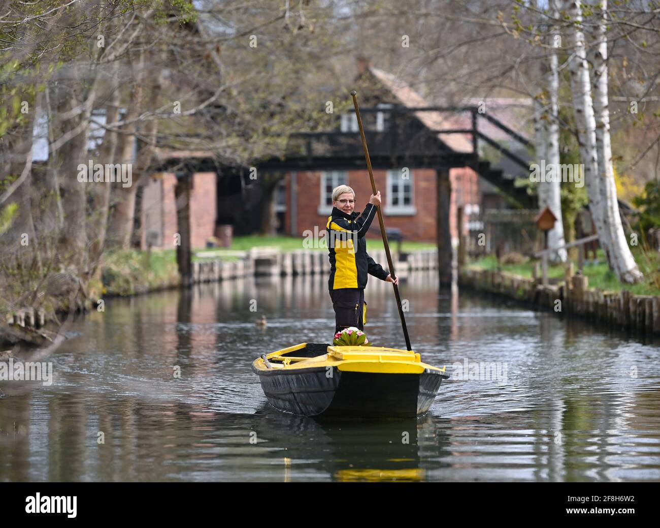 Brandenburg, Lehde: 14. April 2021, Andrea Bunar, Postzustellerin, ist mit ihrem gelben Briefkahn zu Beginn der Postzustellsaison auf einem Fluss (Wasserweg im Spreewald). Die Postträgerin Andrea Bunar bringt in der Corona-Pandemie ein wenig Normalität in den Spreewald: Seit Mittwoch (14.04.2021) liefert sie wieder Briefe und Pakete an Bewohner auf ihrem Lastkahn. Die 50-Jährige liefert an 65 Haushalte, sie steuert ihren Lastkahn auf der rund acht Kilometer langen Tour allein mit Muskelkraft. (Zu dpa: 'Briefträger mit Muskelkraft: Post kommt wieder im Spreewald b Stockfoto