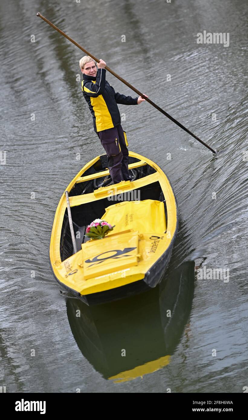 Brandenburg, Lehde: 14. April 2021, Andrea Bunar, Postzustellerin, ist mit ihrem gelben Briefkahn zu Beginn der Postzustellsaison auf einem Fluss (Wasserweg im Spreewald). Die Postträgerin Andrea Bunar bringt in der Corona-Pandemie ein wenig Normalität in den Spreewald: Seit Mittwoch (14.04.2021) liefert sie wieder Briefe und Pakete an Bewohner auf ihrem Lastkahn. Die 50-Jährige liefert an 65 Haushalte, sie steuert ihren Lastkahn auf der rund acht Kilometer langen Tour allein mit Muskelkraft. (Zu dpa: 'Briefträger mit Muskelkraft: Post kommt wieder im Spreewald b Stockfoto