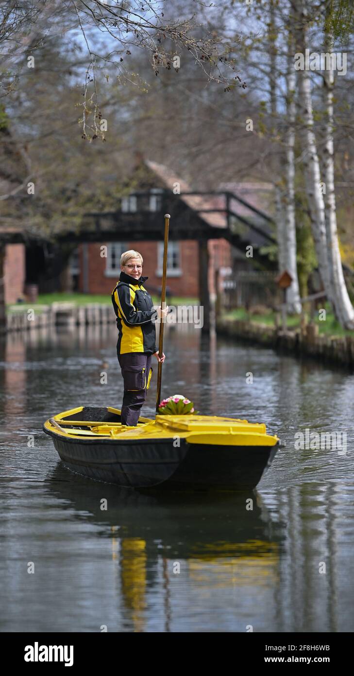 Brandenburg, Lehde: 14. April 2021, Andrea Bunar, Postzustellerin, ist mit ihrem gelben Briefkahn zu Beginn der Postzustellsaison auf einem Fluss (Wasserweg im Spreewald). Die Postträgerin Andrea Bunar bringt in der Corona-Pandemie ein wenig Normalität in den Spreewald: Seit Mittwoch (14.04.2021) liefert sie wieder Briefe und Pakete an Bewohner auf ihrem Lastkahn. Die 50-Jährige liefert an 65 Haushalte, sie steuert ihren Lastkahn auf der rund acht Kilometer langen Tour allein mit Muskelkraft. (Zu dpa: 'Briefträger mit Muskelkraft: Post kommt wieder im Spreewald b Stockfoto