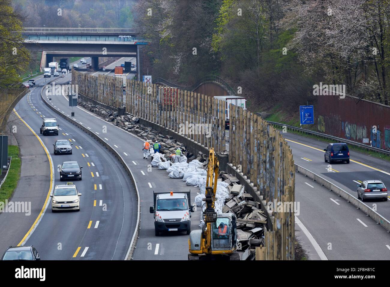 Sanierung Laermschutzwand auf der A52. Mehrere Arbeiter in Schutzangriffen und Atemmaske frachten den Inhalt von Schallschutzelementen in weisse SAE Stockfoto