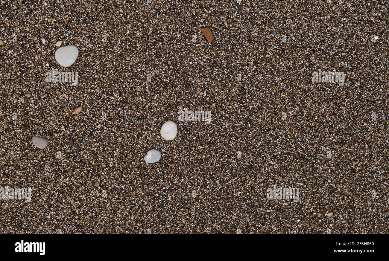 Sand und kleine runde Steine aus der Nähe. Die Küste des Schwarzen Meeres und seine Küste. Minimalistischer Sandhintergrund und Platz für Text- oder Werbegestaltung. Stockfoto