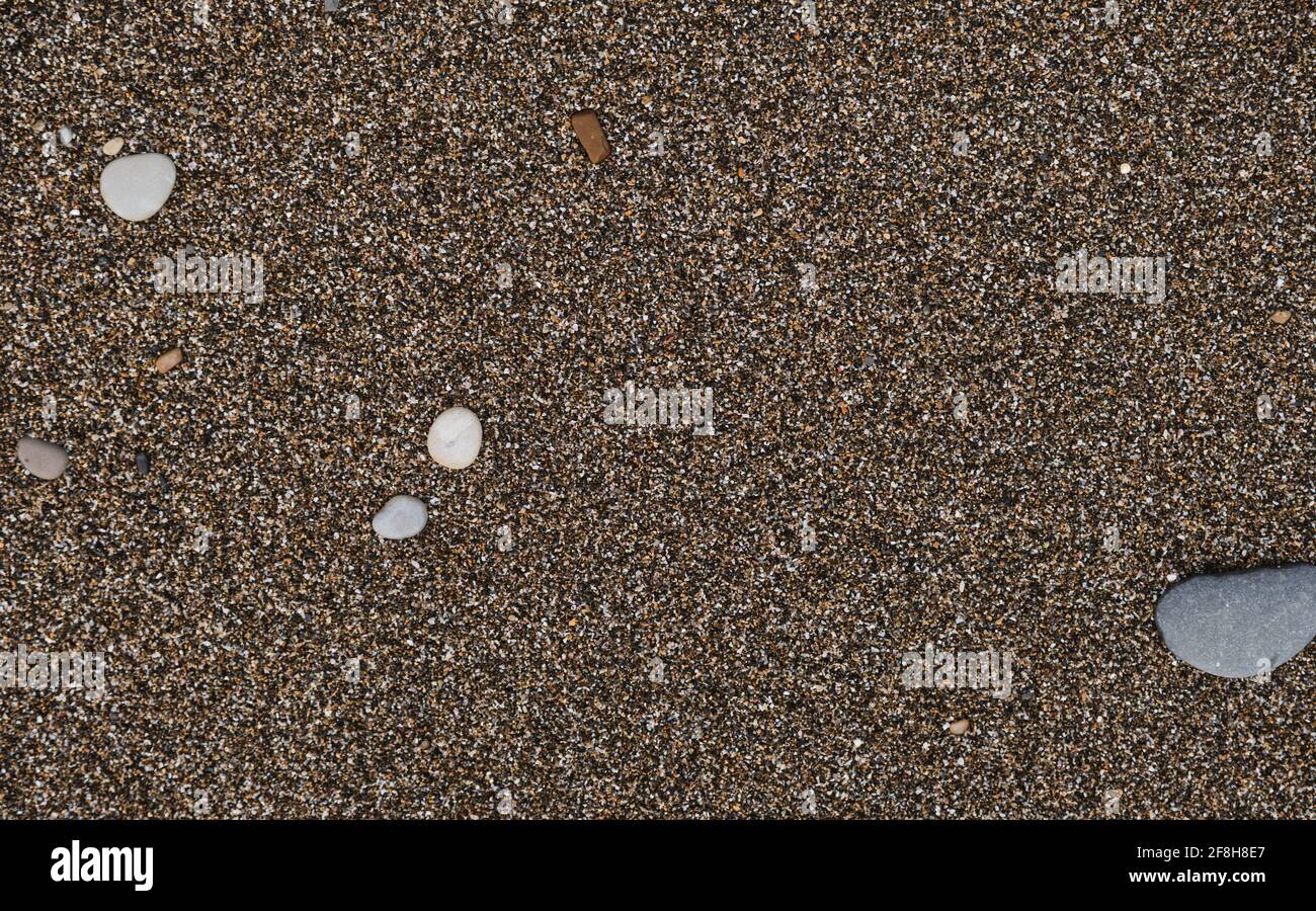 Sand und kleine runde Steine aus der Nähe. Die Küste des Schwarzen Meeres und seine Küste. Minimalistischer Sandhintergrund und Platz für Text- oder Werbegestaltung. Stockfoto