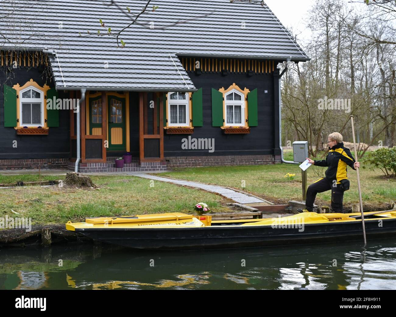 14. April 2021, Brandenburg, Lübbenau: Andrea Bunar, Postzustellerin, ist mit ihrem gelben Briefkahn zu Beginn der Postzustellsaison auf einem Fluss (Wasserweg im Spreewald). Die Postträgerin Andrea Bunar bringt in der Corona-Pandemie ein wenig Normalität in den Spreewald: Seit Mittwoch (14.04.2021) liefert sie wieder Briefe und Pakete an Bewohner auf ihrem Lastkahn. Die 50-Jährige liefert an 65 Haushalte, sie steuert ihren Lastkahn auf der rund acht Kilometer langen Tour allein mit Muskelkraft. (Zu dpa: 'Briefträger mit Muskelkraft: Post kommt wieder in den Spreewald Stockfoto
