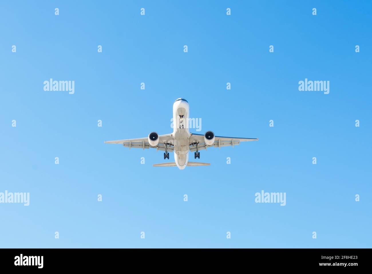 Düsenflugzeug, das in blauem Himmel fliegt, nähert sich für die Landung Stockfoto