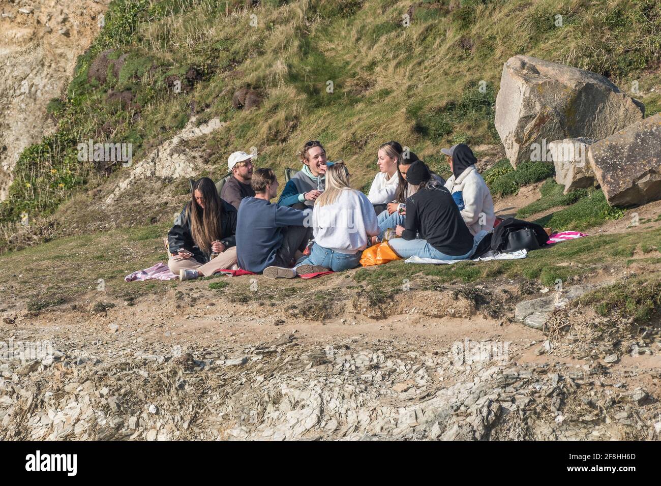 Eine Gruppe junger Leute, die zusammen sitzen und sich im Little Fistral in Newquay in Cornwall treffen. Stockfoto