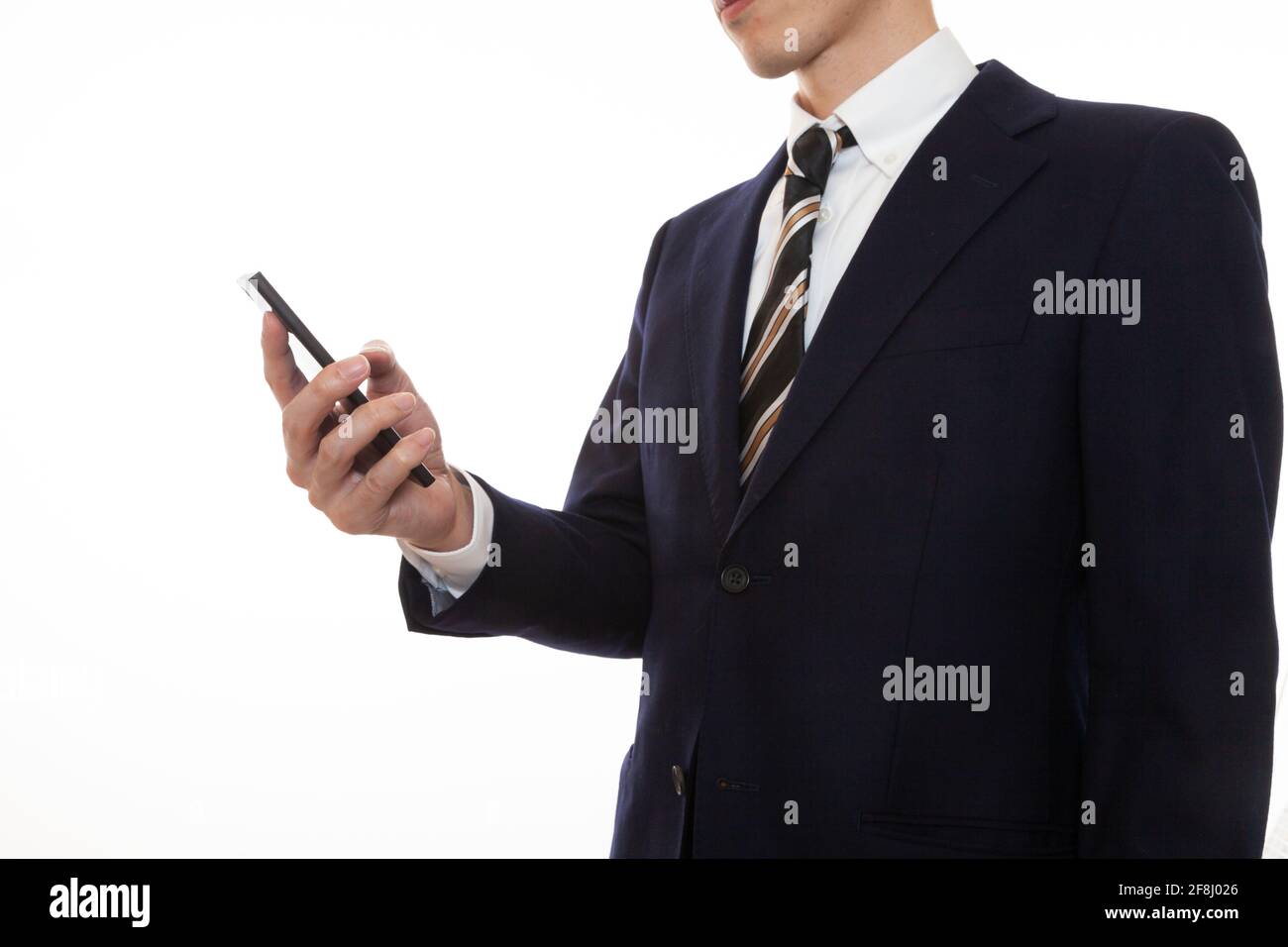 Ein Mann in einem Anzug, der ein Smartphone in seinem Gerät betreibt Rechte Hand Stockfoto