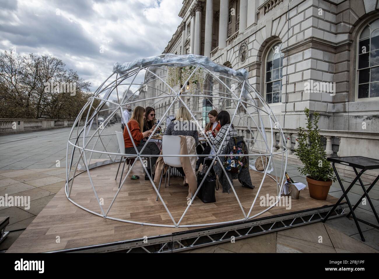 Freunde genießen eine der im Iglu-Stil gehaltenen Gasthäuser des Somerset House, wo Gruppen von bis zu sechs Personen essen und trinken können, während sie die Themse, London, Großbritannien, betrachten Stockfoto