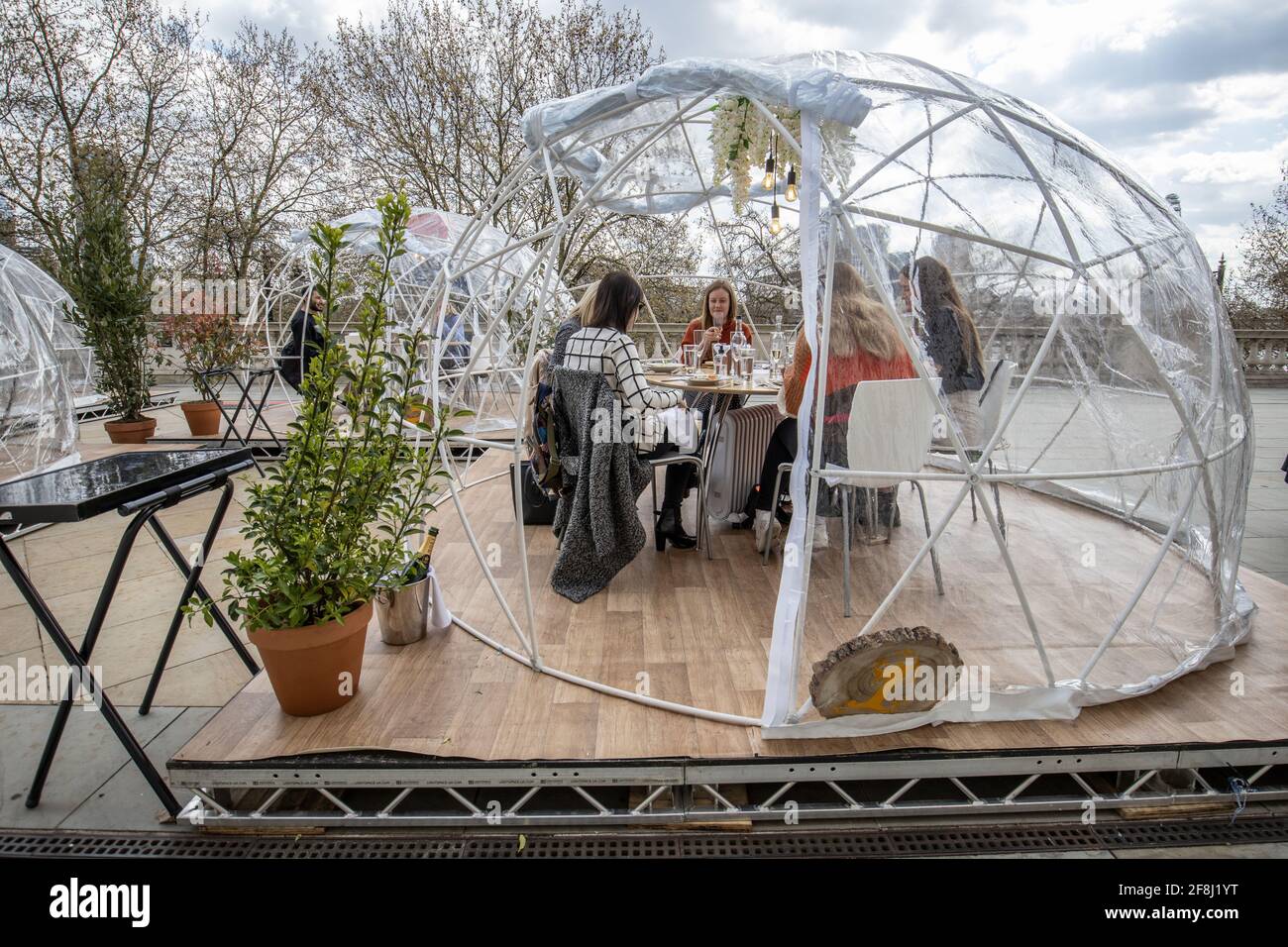 Freunde genießen eine der im Iglu-Stil gehaltenen Gasthäuser des Somerset House, wo Gruppen von bis zu sechs Personen essen und trinken können, während sie die Themse, London, Großbritannien, betrachten Stockfoto