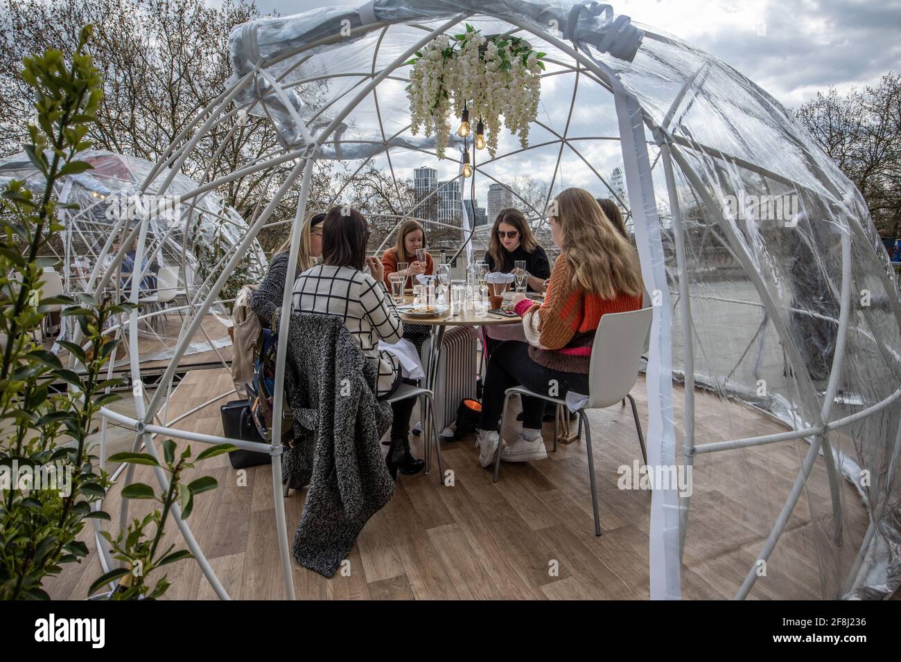 Freunde genießen eine der im Iglu-Stil gehaltenen Gasthäuser des Somerset House, wo Gruppen von bis zu sechs Personen essen und trinken können, während sie die Themse, London, Großbritannien, betrachten Stockfoto