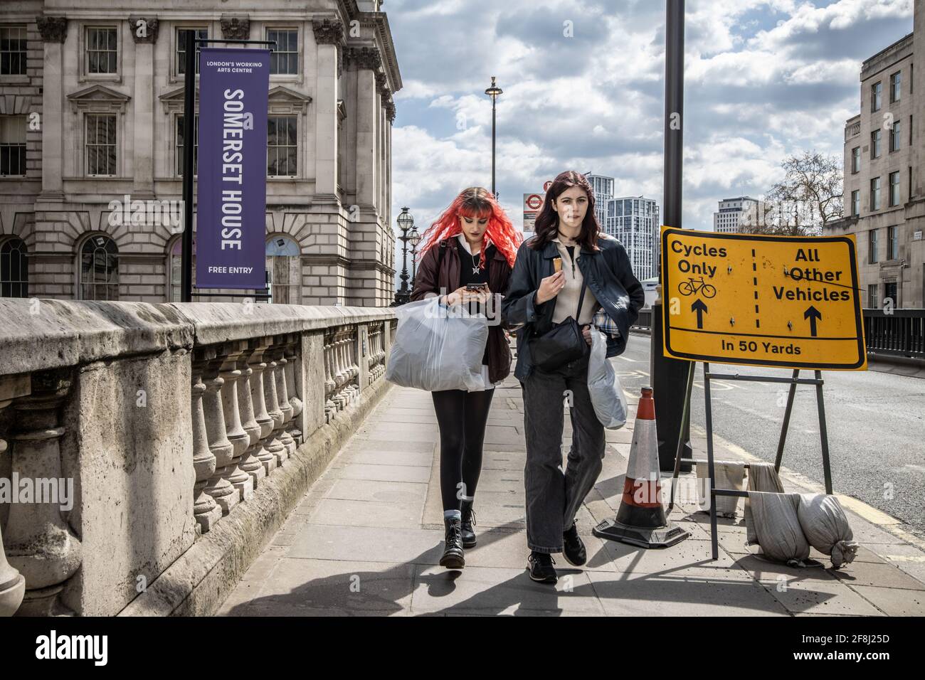 Zwei junge Frauen gehen an einem der Eingänge zum Somerset House entlang der Waterloo Bridge, London, Großbritannien, vorbei Stockfoto