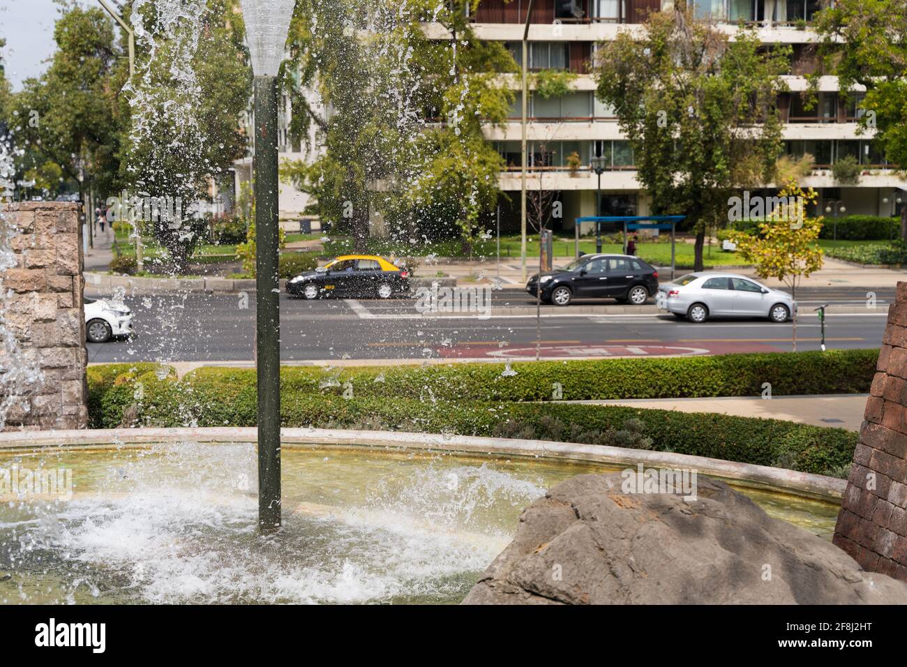 Wasserbrunnen und fließender Verkehr in der Innenstadt von Santiago, Chile. Park und Grünfläche im urbanen Stadtkonzept Stockfoto