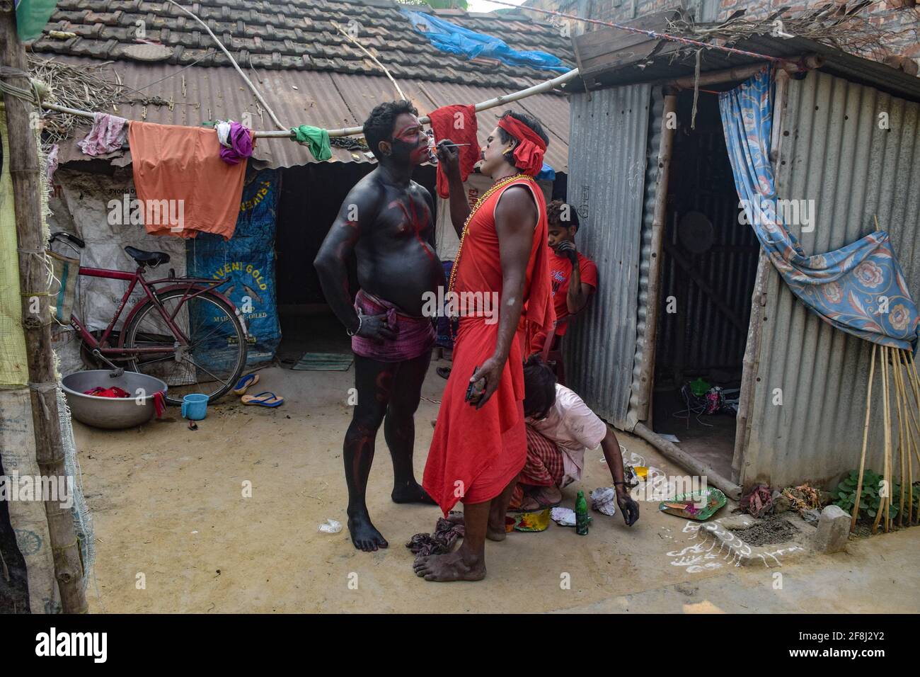 Bardhaman, Indien. April 2021. Während des Gajan-Festivals wird ein Anhänger gesehen, der einen anderen Anhänger malt. Gajan ist ein hinduistisches Fest, das vor allem in Westbengalen sowie im südlichen Teil von Bangladesch gefeiert wird. Das Fest wird mit der Hingabe von Herrn Shiva verbunden. Die Menschen feiern mit Ritualen wie Gesichtsbemalung und Cosplaying. Eifrige Anhänger verkleiden sich als hinduistische mythologische Figuren und führen von Tür zu Tür verschiedene mythologische Geschichten auf. Kredit: SOPA Images Limited/Alamy Live Nachrichten Stockfoto