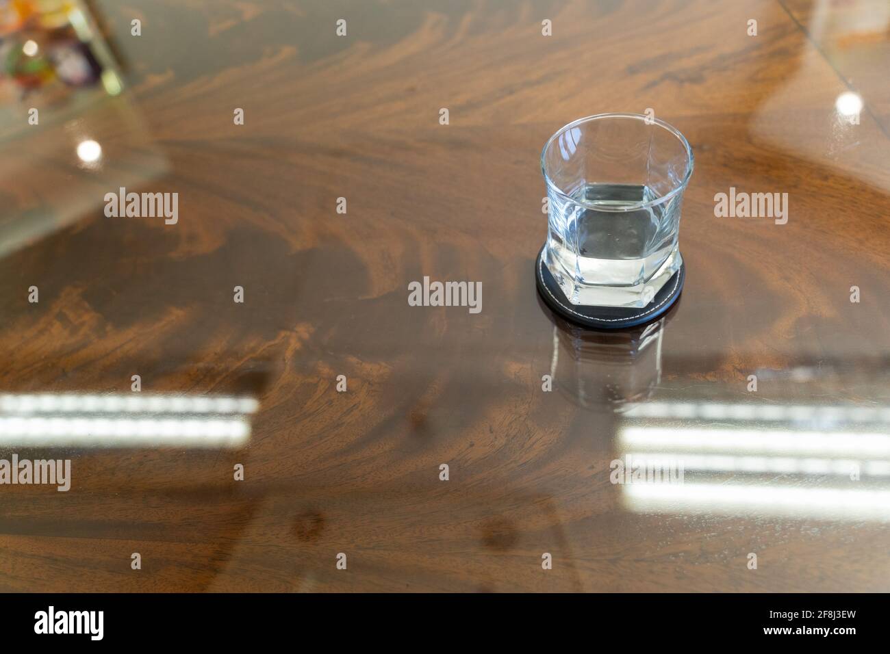 Wasserglas auf Achterbahn auf leeren Tisch mit Reflexion platziert Stockfoto
