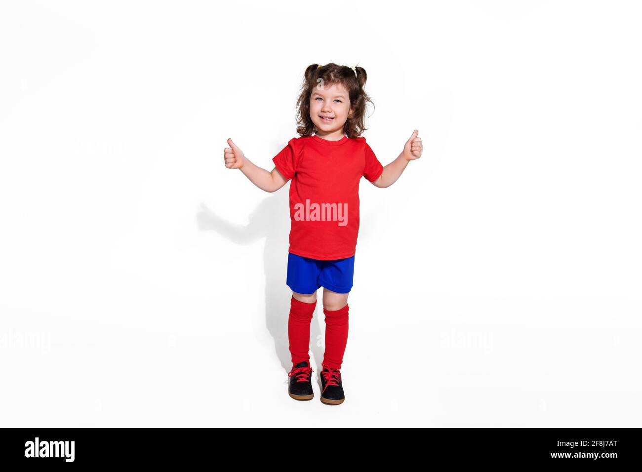 Kleine schöne Mädchen 5 Jahre in Fußball-Uniform isoliert auf weißem Hintergrund Blick auf die Kamera. Frauenfußballkonzept für Kinder. Foto für Adverti Stockfoto