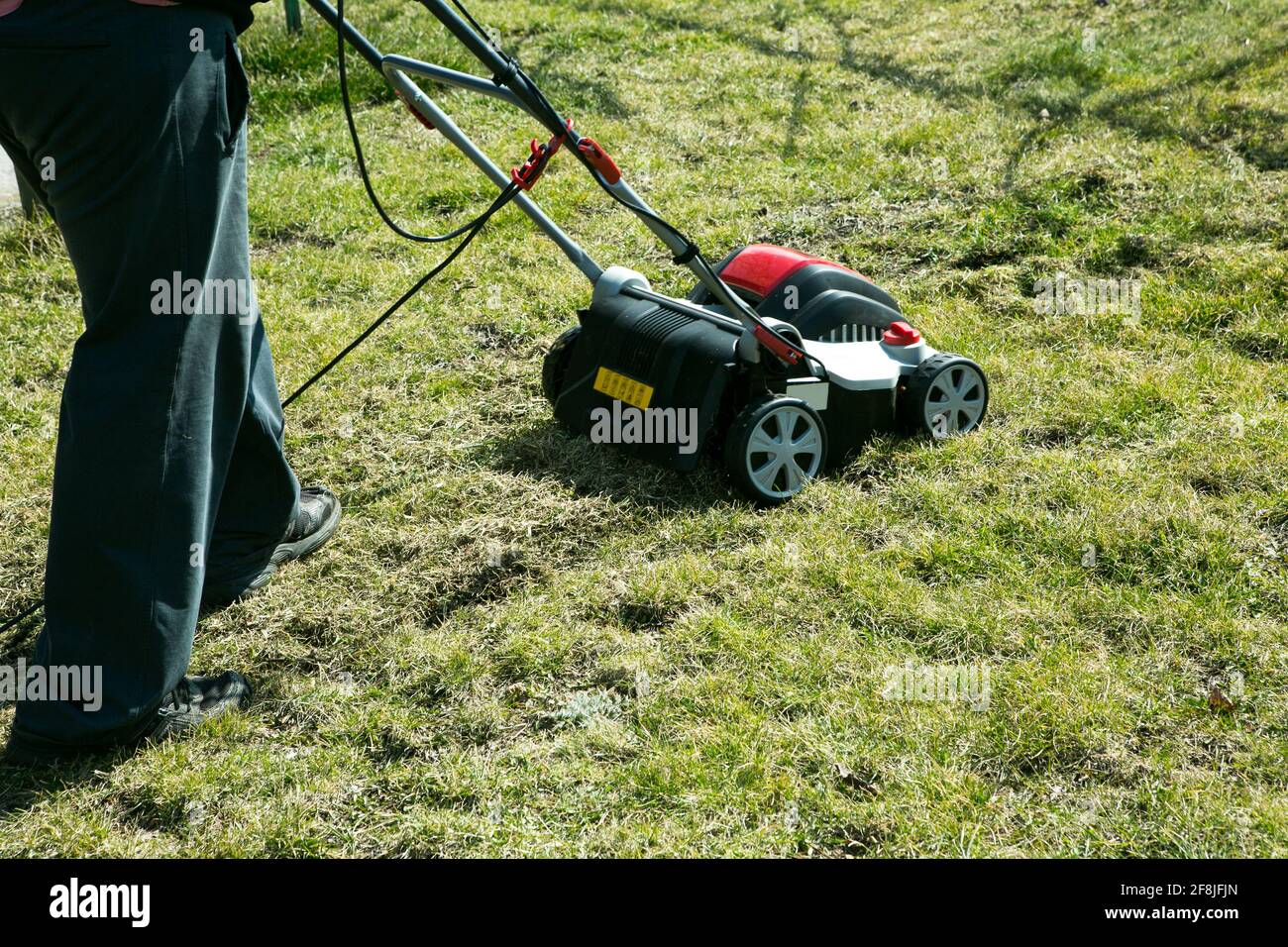 Belüftung mit einem Vertikutierer. Mit einem Scarifier im Garten zur Verbesserung der Rasenqualität im Frühjahr. Ein Arbeiter, Gärtner Betrieb Bodenbelüftung Stockfoto