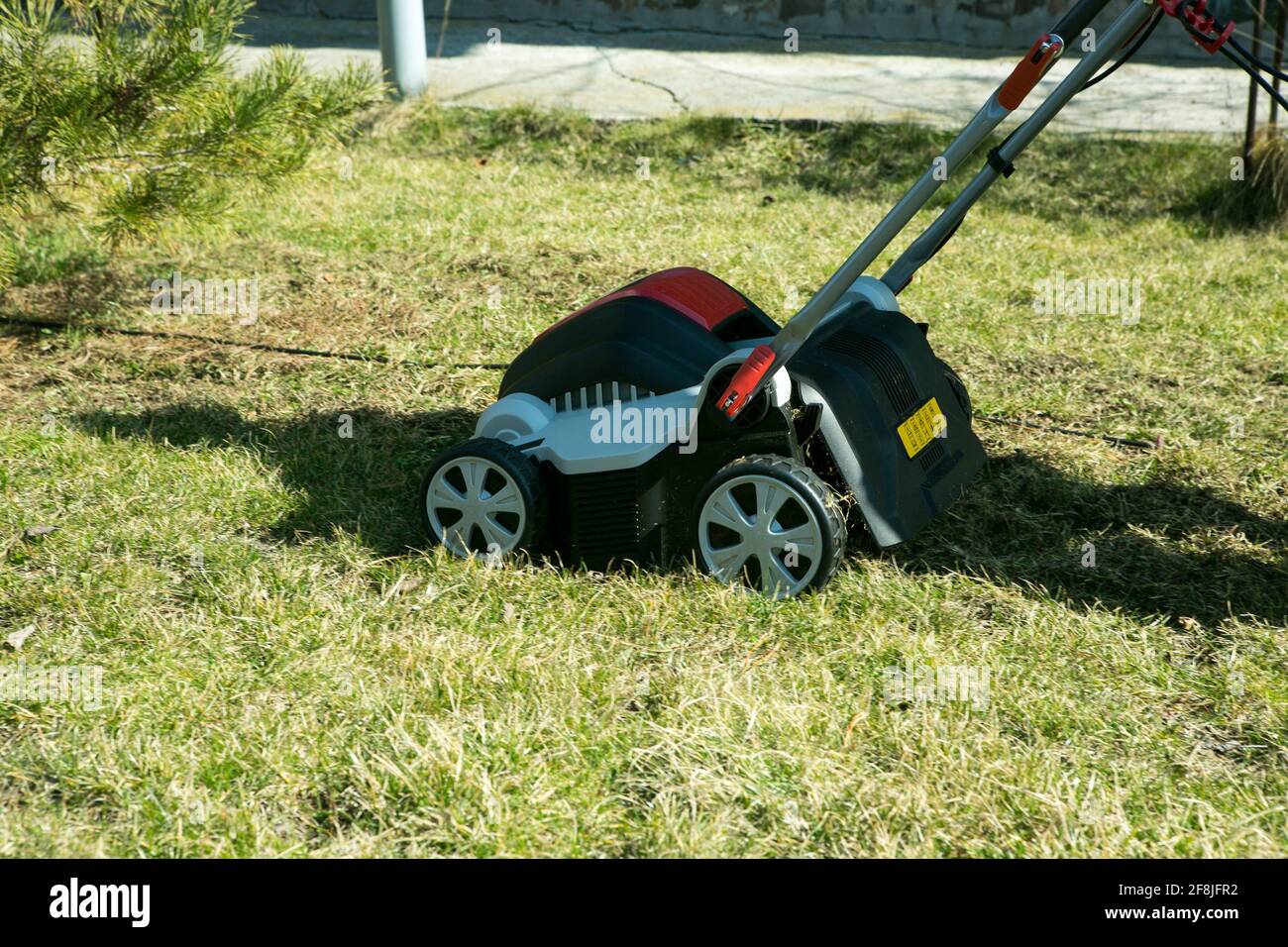 Belüftung mit einem Vertikutierer. Mit einem Scarifier im Garten zur Verbesserung der Rasenqualität im Frühjahr. Ein Arbeiter, Gärtner Betrieb Bodenbelüftung Stockfoto