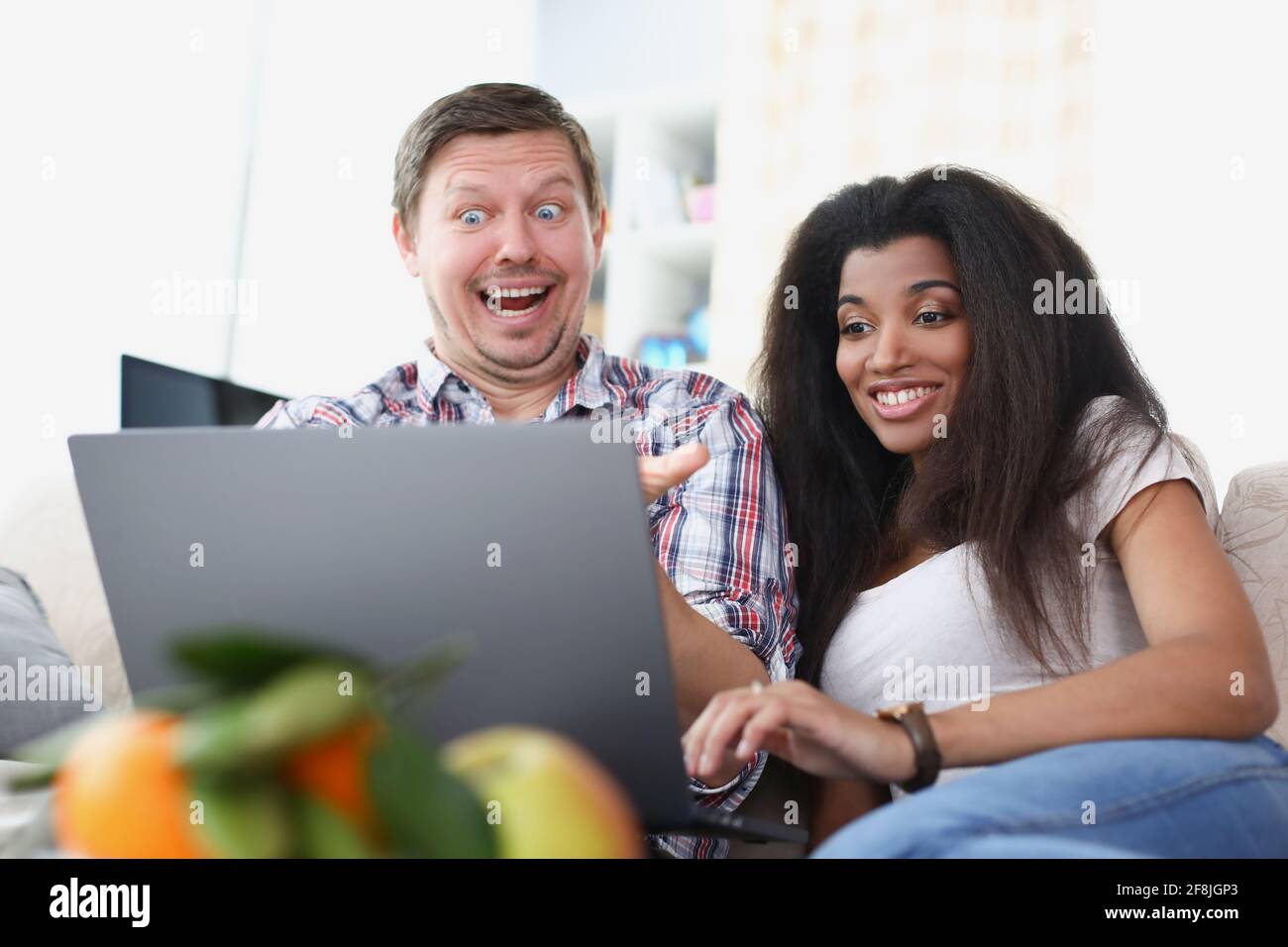 Junge Männer und Frauen sitzen vor dem Laptop Bildschirm und Lächeln Stockfoto