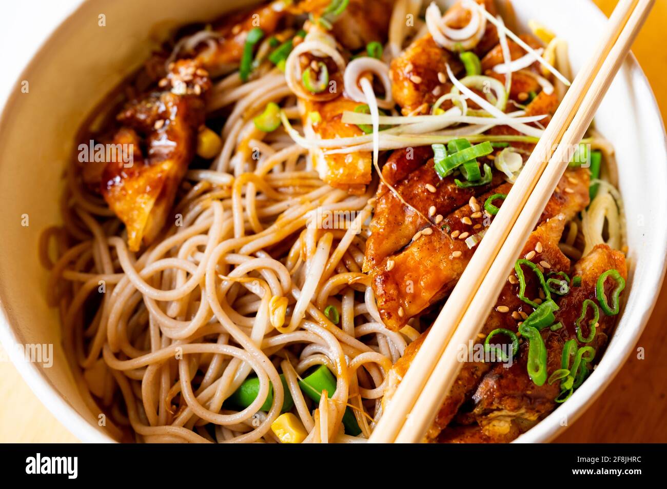 Schüssel mit Soba-Nudeln, Hühnerfleisch, grünen Zwiebeln, Sprossen und Sesam mit Essstäbchen, asiatische (japan) Mahlzeit. Portion für eine Person zum Mitnehmen, Ramen. Stockfoto