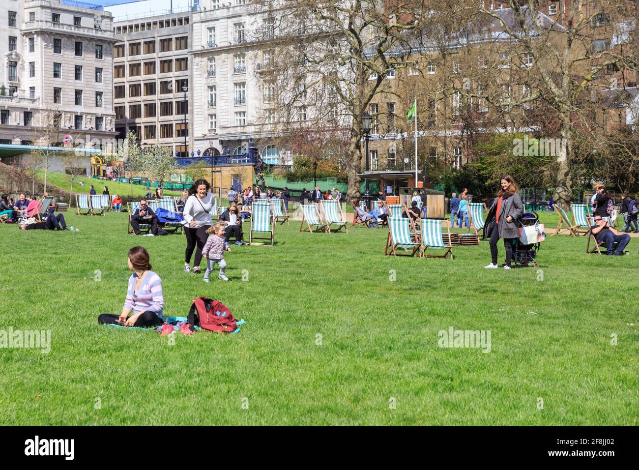 In Green Park, London, England, Großbritannien, entspannen sich die Menschen in Liegestühlen, sonnen sich und genießen Picknicks Stockfoto